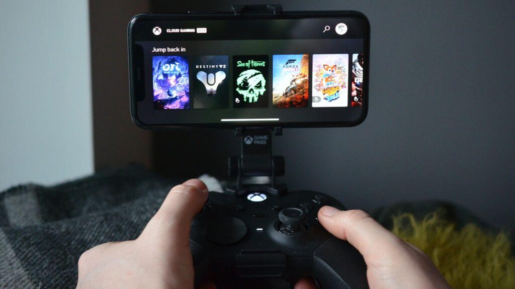 A picture of a player playing games on his smartphone with an Xbox controller using cloud gaming